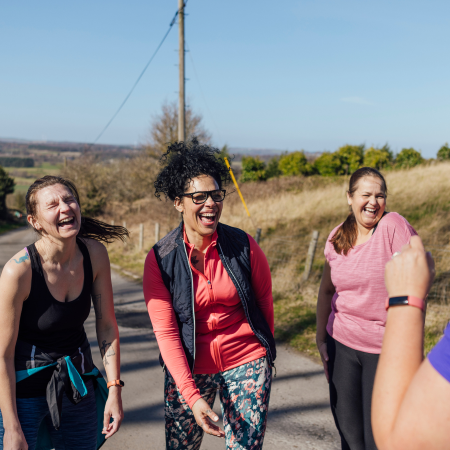 3 women walking and laughing in the countryside